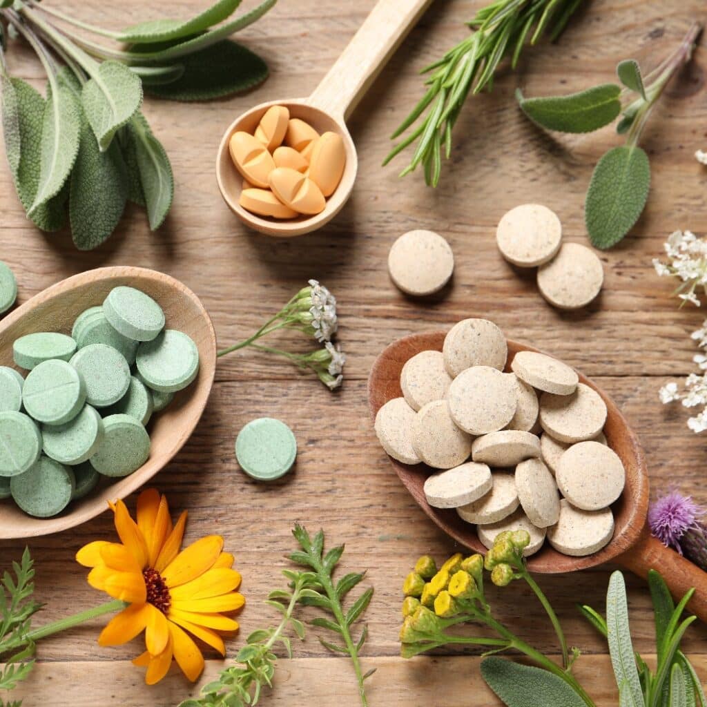 Verschiedene Pillen, Kräuter und Blumen auf einem Holztisch, flach gelegt. Nahrungsergänzungsmittel